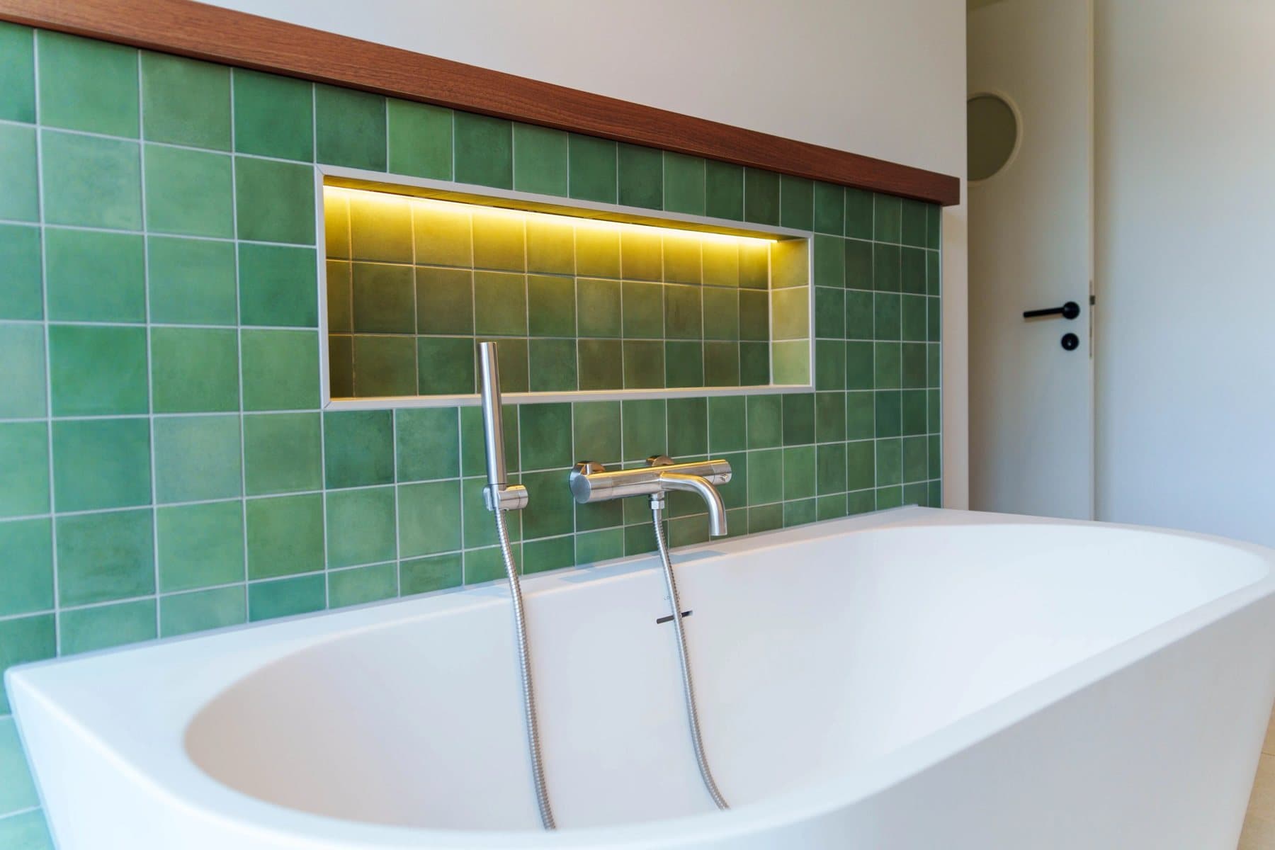 Green bathroom with freestanding bath and lit niche