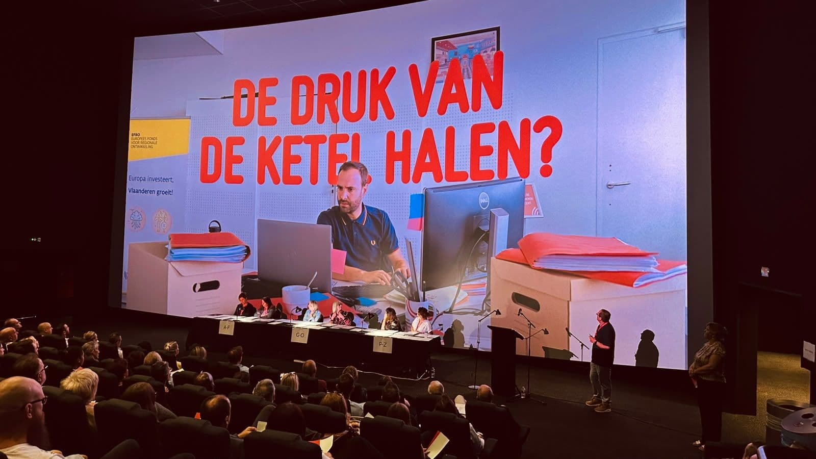 De film met de tekst ‘De druk van de ketel halen?’ op het bioscoopscherm tijdens de diplomahappening